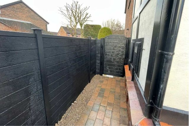 Black composite fencing and an arched-top composite gate in a narrow side passage in Hucknall