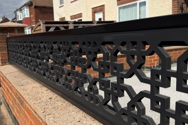 Close detail of the cathedral trellis pattern on a black composite wall topper in Long Eaton