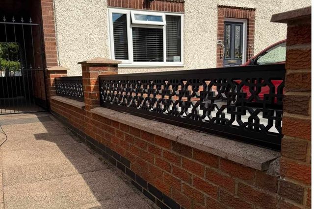 Black cathedral design composite trellis toppers mounted along a low brick wall in Long Eaton
