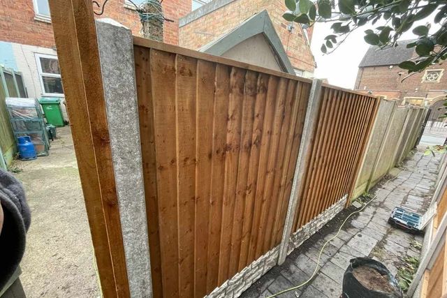 Closeboard fence panels being fitted into concrete posts with rock-faced gravel boards in West Bridgford