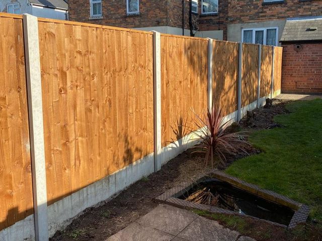 New closeboard fence panels with concrete posts and gravel boards beside a garden pond in Carlton