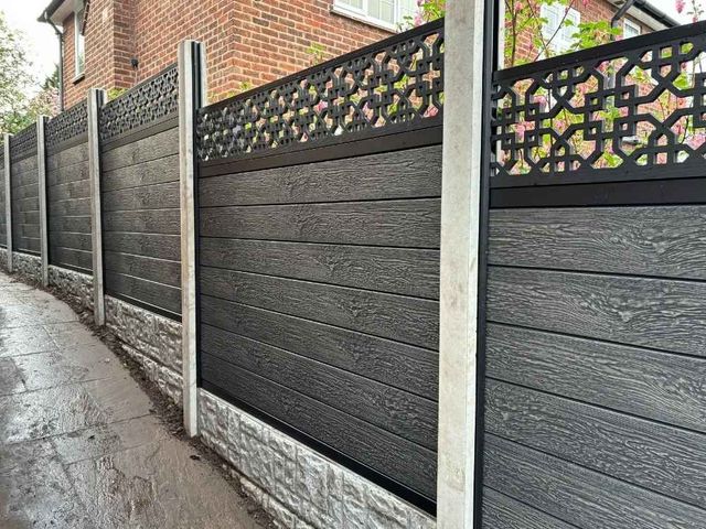 Dark composite fencing with cathedral screen toppers running along an alleyway with concrete posts