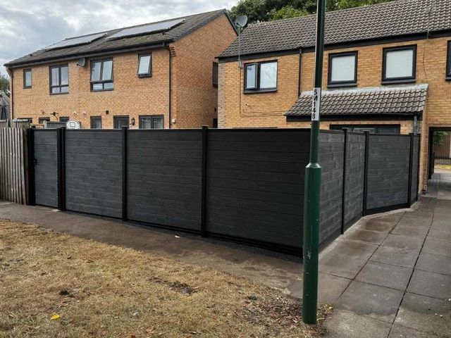 Black composite fencing with a matching composite gate on a corner plot
