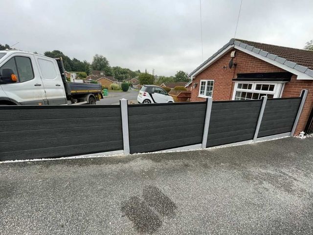 Anthracite grey composite fencing with a black frame fitted into concrete posts beside a bungalow driveway