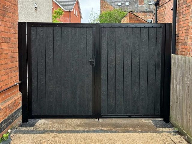 Black composite double gates with a black frame fitted between brick walls on a Nottingham driveway