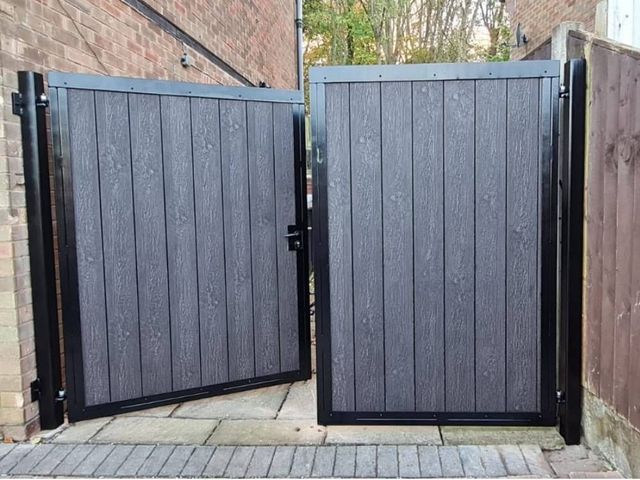 Anthracite grey composite driveway gates standing part open on block paving