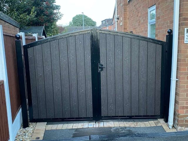 Arched top composite driveway gates with ball finials on the posts