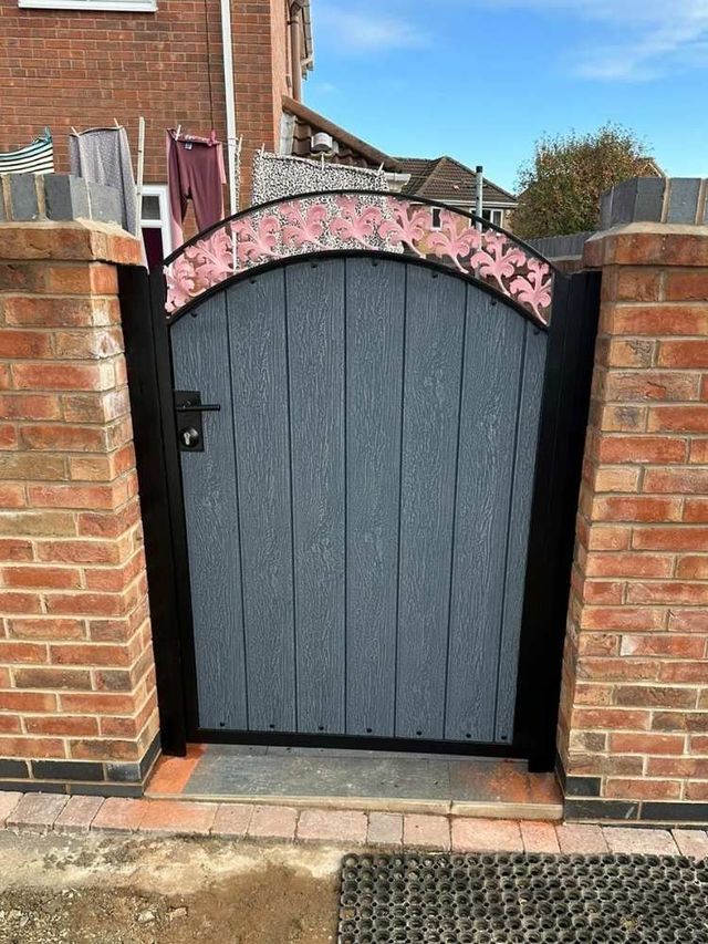 Grey arched composite pedestrian gate with a pink floral decorative panel above