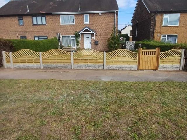 Arched hit and miss fence panels with trellis tops and a matching gate along a front garden boundary in concrete posts