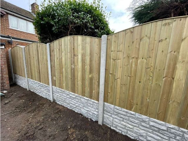 Arched top tongue and groove timber fence panels on concrete posts with rock faced gravel boards
