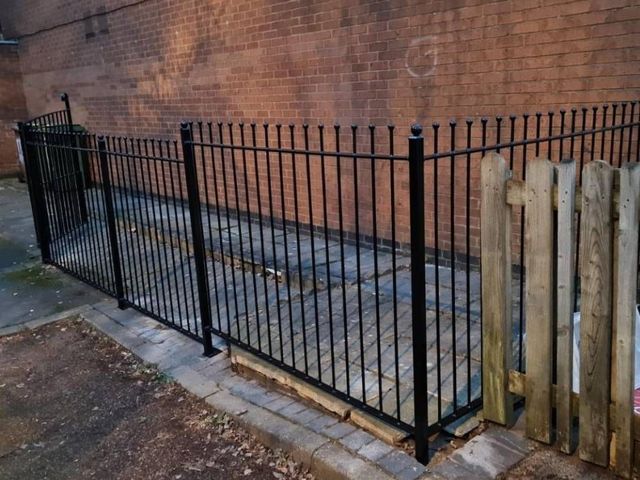Black ball top metal railings enclosing a yard outside a business premises in Nottingham
