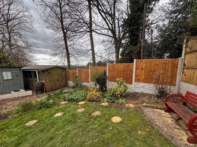 Closeboard fence panels stepping down in level bays with rock faced gravel boards beside a garden shed in Eastwood