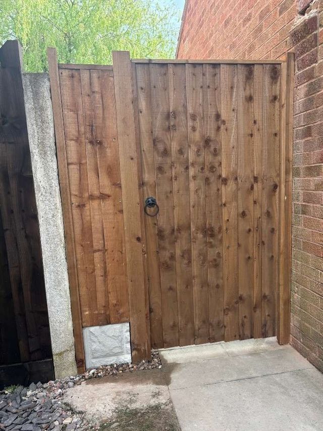Closeboard wooden garden gate hung beside a matching fixed closeboard panel filling the rest of a wide opening