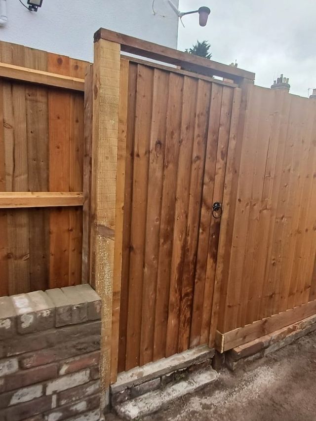 Closeboard wooden garden gate framed into a run of closeboard fencing with its own posts and head rail, mid installation