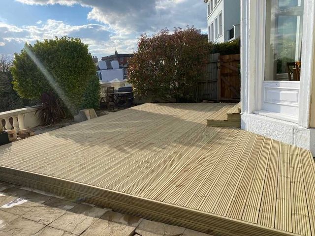Side view of the finished timber deck showing the fascia board along the edge where it meets the original flagstones