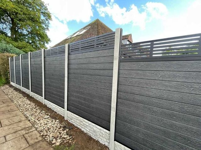 Composite fencing with a horizontal bar screen top fitted into concrete posts and rock-faced gravel boards