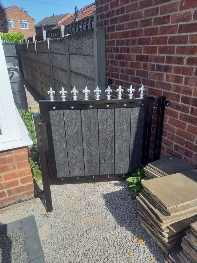 Low grey composite front garden gate with silver fleur de lis finials along the top