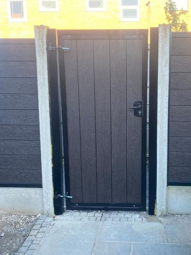 Walnut composite pedestrian gate hung between matching composite fence panels and concrete posts