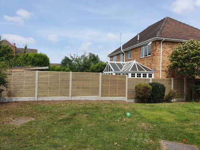 Slatted fence panels in concrete posts with rock faced gravel boards along a rear garden boundary
