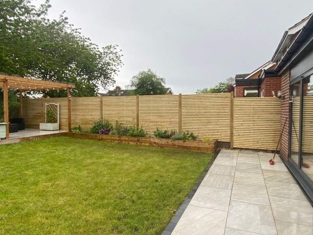 Slatted fence panels with matching timber posts around a newly landscaped garden with sleeper beds