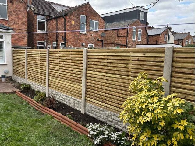 Double sided slatted fencing with slats on both faces of the frame, in concrete posts with rock faced gravel boards