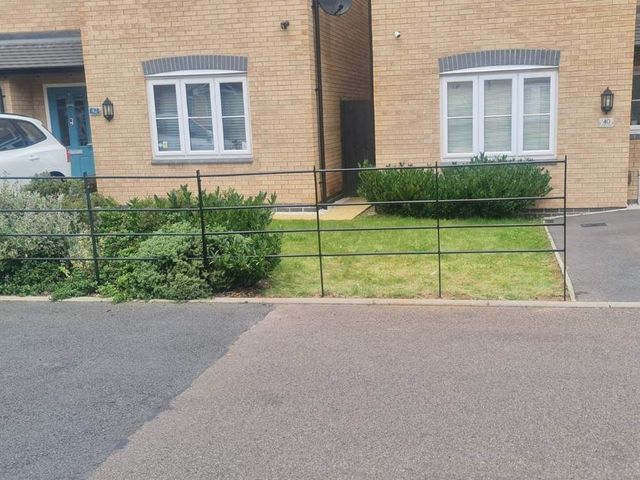 Estate style metal railings with horizontal rails across a front garden on a modern development
