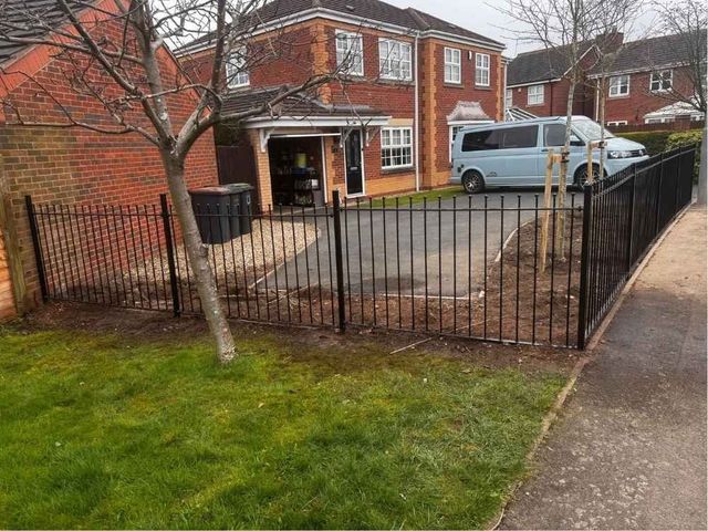 Ball top metal railings enclosing a front garden and driveway outside a detached house
