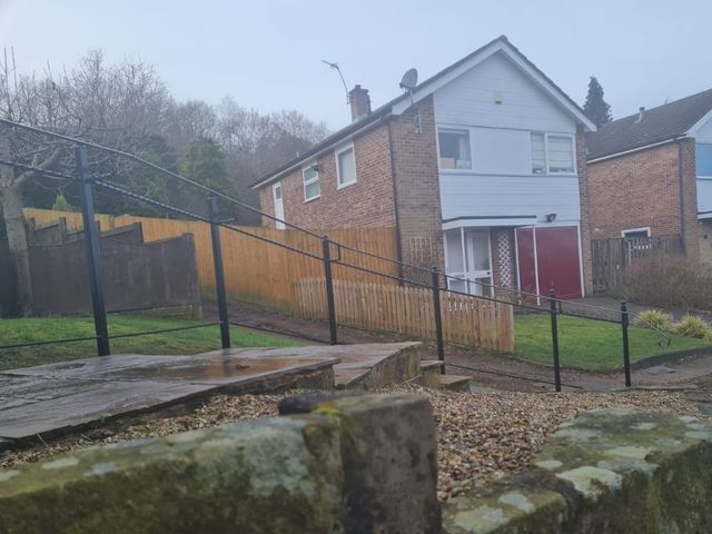 Long black metal handrail with twisted bar running down a sloping front garden path
