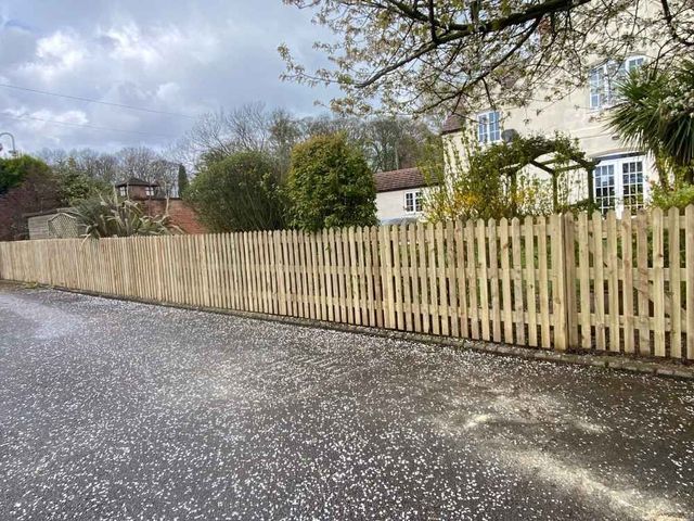 Low round top picket fencing along a cottage frontage following the fall of the lane with a matching gate