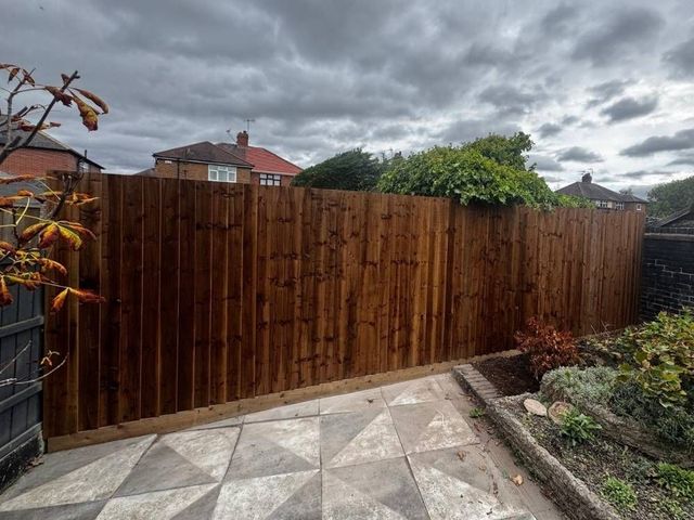 Dark treated closeboard featheredge fencing enclosing a rear garden with a patio in Nottingham