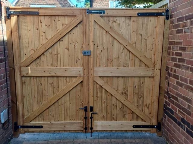 The same tongue and groove gates from inside showing the braced frame, black strap hinges and twin drop bolts