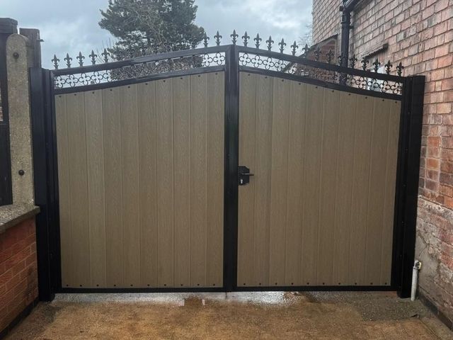 Natural oak coloured composite driveway gates with a decorative fleur de lis frieze in Long Eaton