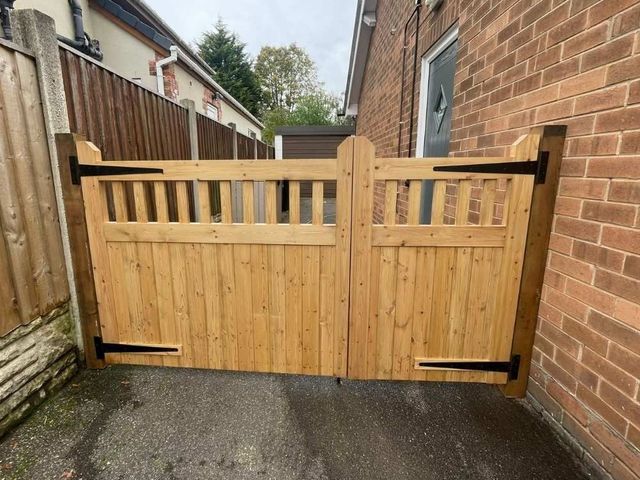 Offset wooden driveway gates with one narrow leaf and one wide leaf, spindle topped, seen from the drive entrance