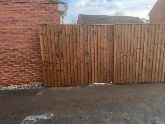 Closeboard timber fencing with a matching gate and ring latch beside a brick house