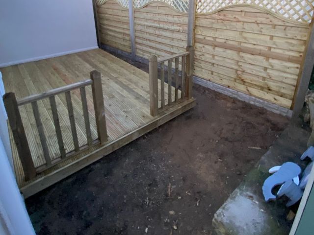 Raised timber deck with square spindle balustrade and new arched trellis topped fence panels behind, photographed before landscaping