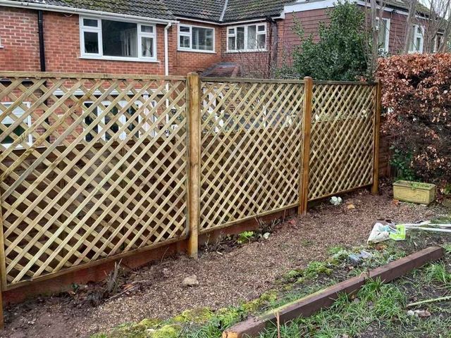 Diamond trellis fence panels on timber posts set alongside an existing low brick wall in a rear garden