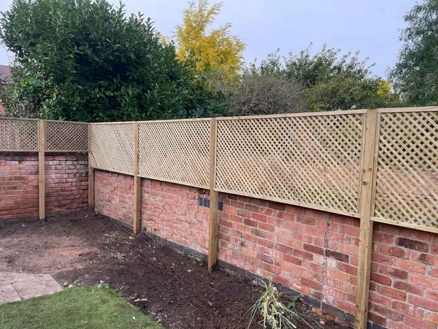 Diamond trellis panels raising the height of a red brick garden wall, seen from inside the garden