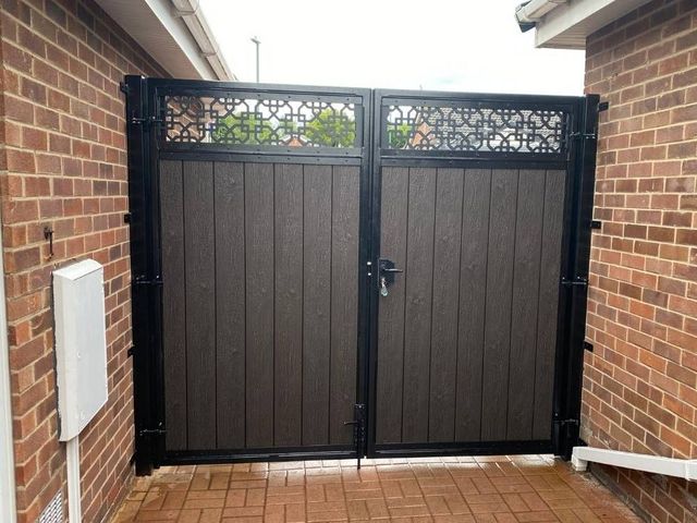 Walnut composite driveway gates with a cathedral design screen top between brick walls