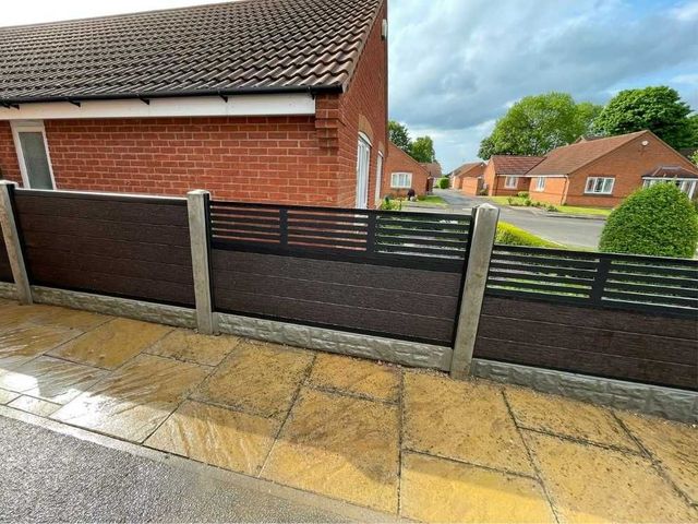 Walnut brown composite fencing with a slatted composite screen top on concrete posts, alongside a bungalow driveway
