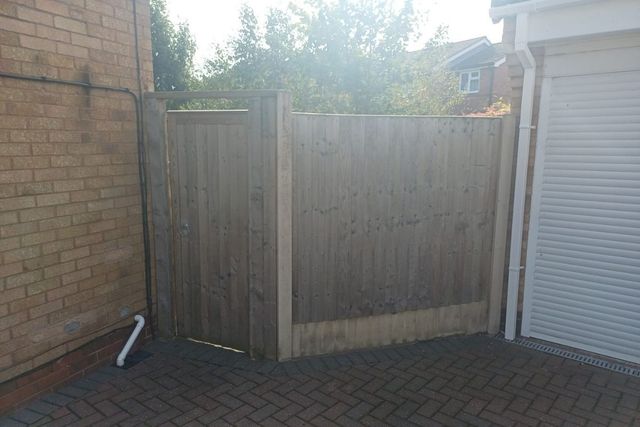 Weathered grey timber fence panels and gate in Long Eaton before replacement