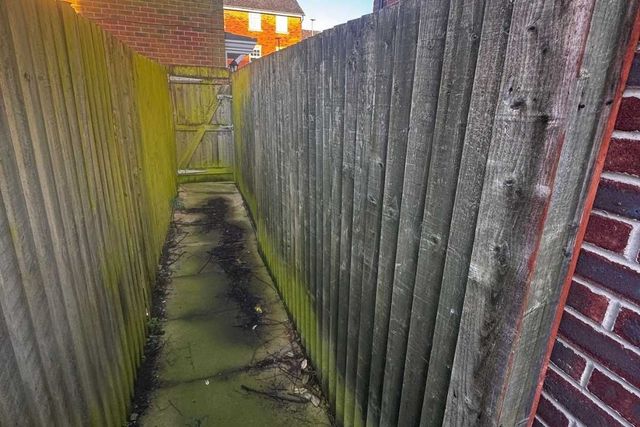 A narrow side passage in West Bridgford with algae-covered timber fencing before replacement