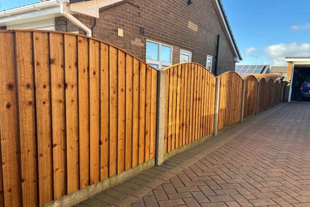 Arched top wooden fence panels running alongside a block paved driveway in Mansfield