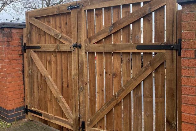 Ledged and braced wooden double gates hung between brick piers in Bulwell