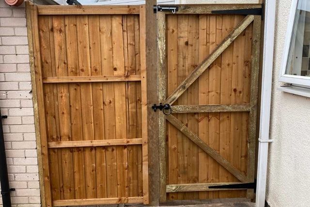 Ledged and braced timber double gates fitted between a brick wall and a house in Hucknall