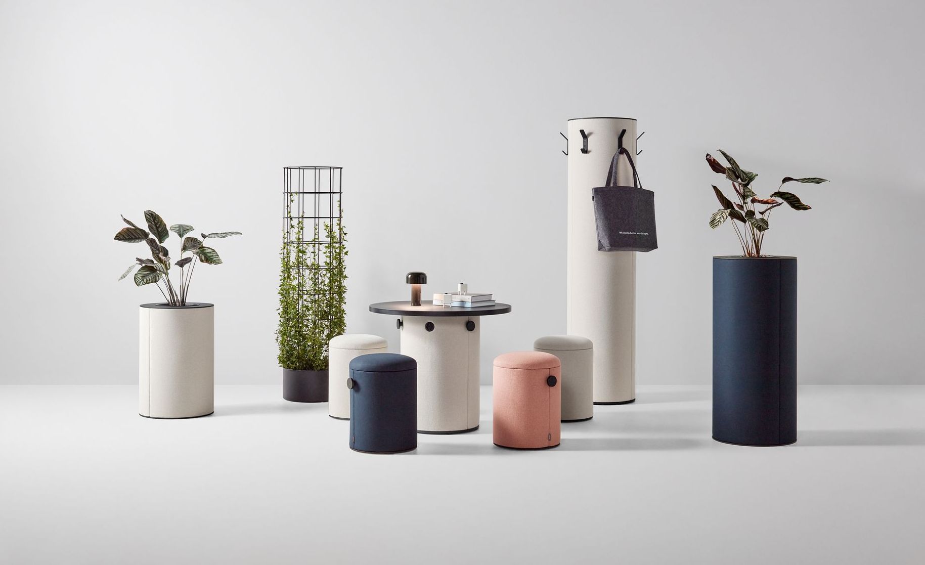 A neutral-toned studio setting with modern cylindrical furniture and plants.