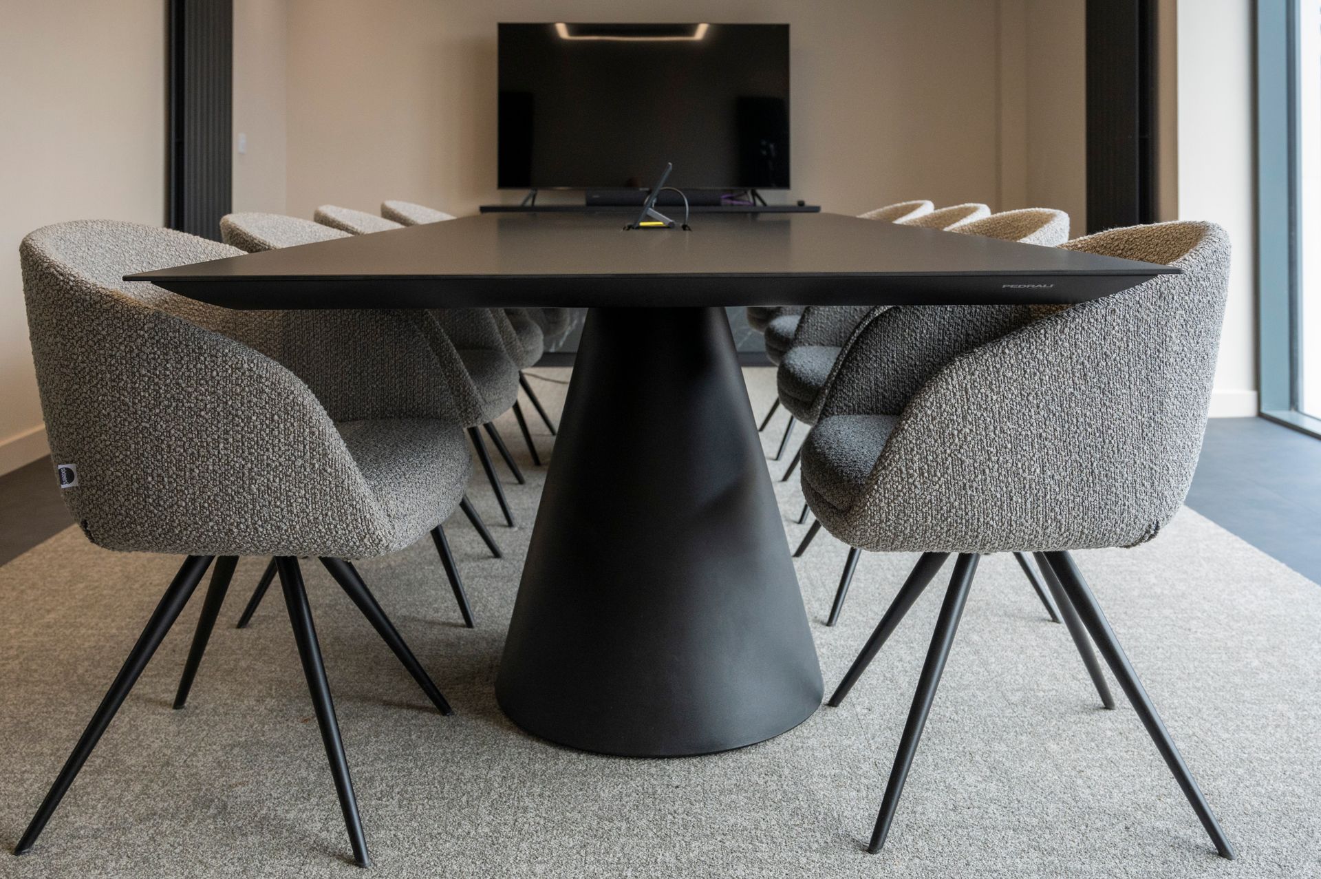 A conference room with a table and chairs and a flat screen tv.