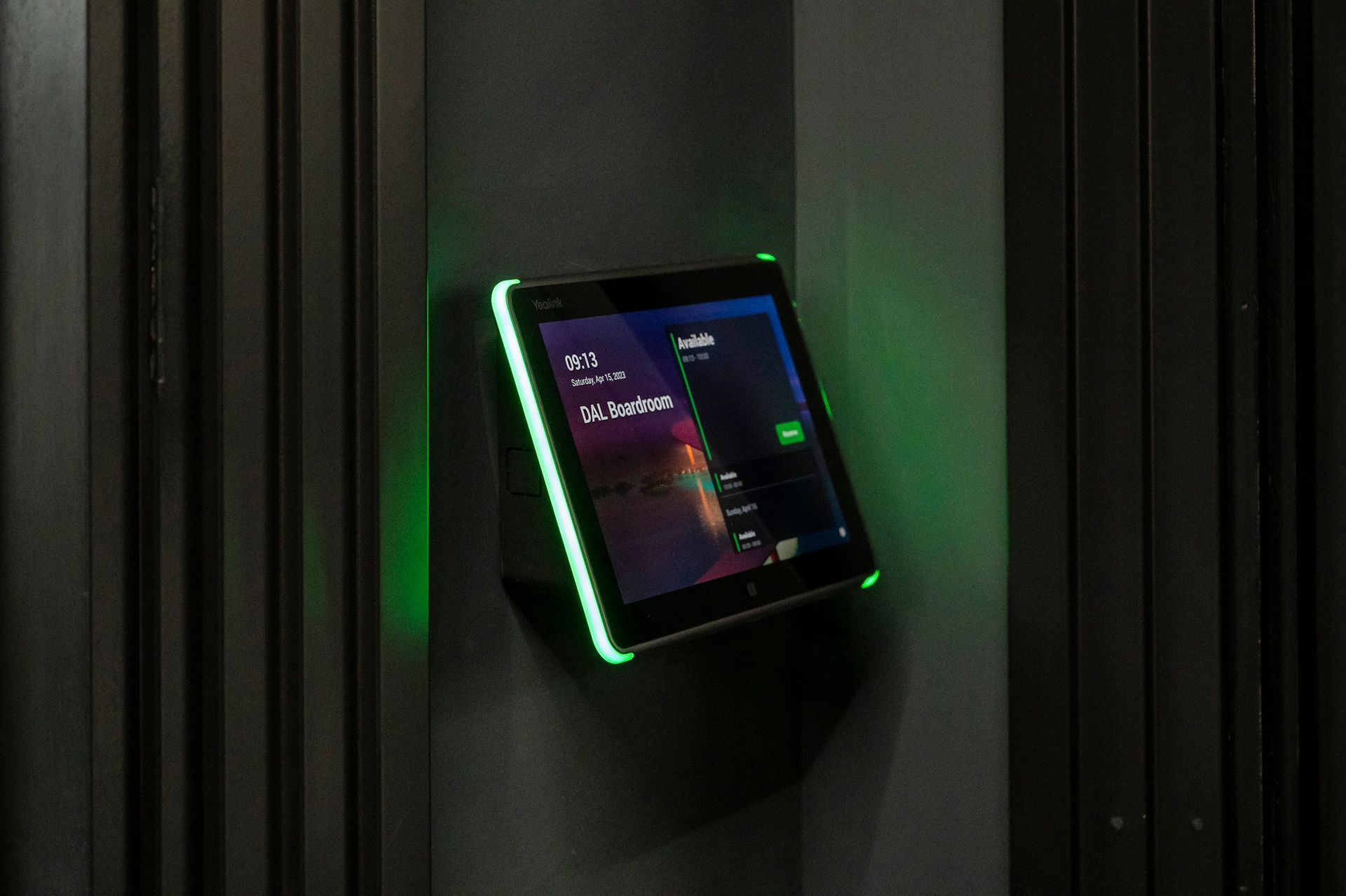 A tablet is hanging on a wall with a green light on it.