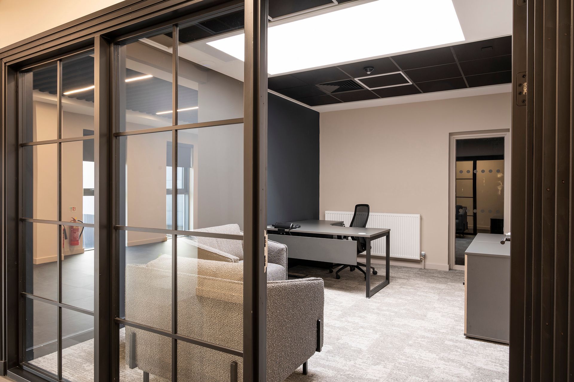 A room with a desk , chair , and sliding glass doors.