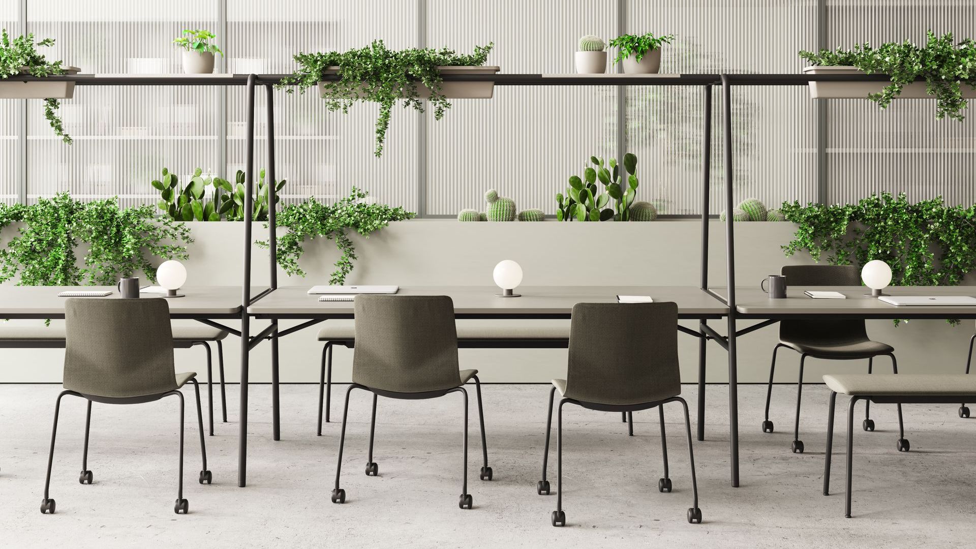 four beige chairs on wheels at desks covered in grenery, like catcus and ivy. on the tables are laptops, notebooks, mugs and lights.