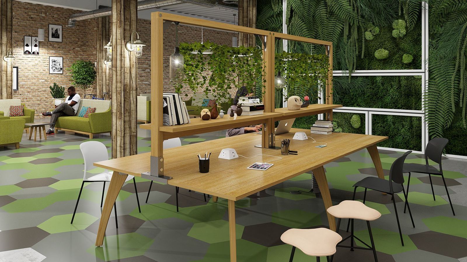 there is a wooden table in the middle of a green and brown office. the table has greenery growing over the lights to create a lush atmosphere. the wall behind the table is covered in thriving greenery. there is a person working at a laptop at the desk. in the background, another person is sitting comfortably on a sofa looking at his phone. 